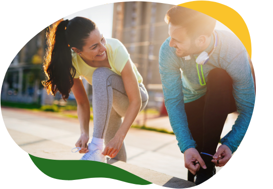 A woman and a man looking at each other while kneeling on the side of the road and tying their jogging shoes