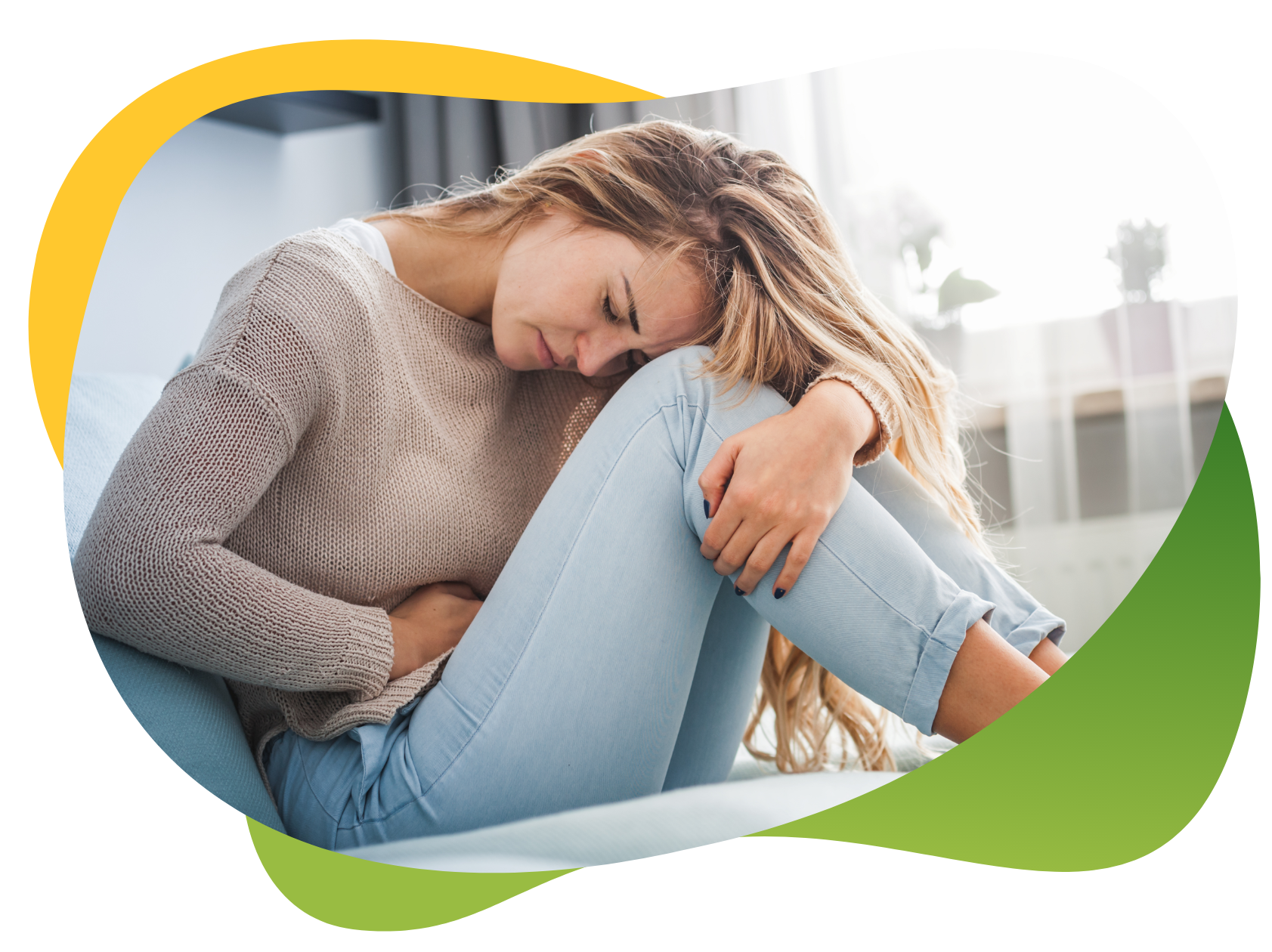 A young woman suffering from period bloating and sitting cramped on the floor holding her abdomen with her left hand