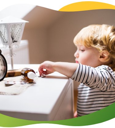 A blonde toddler reaches for a medicine bottle placed on the sideboard