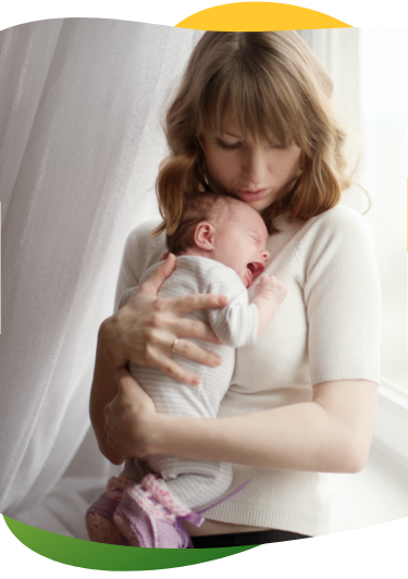 A young mother presses her crying baby to her chest to soothe it from baby colic