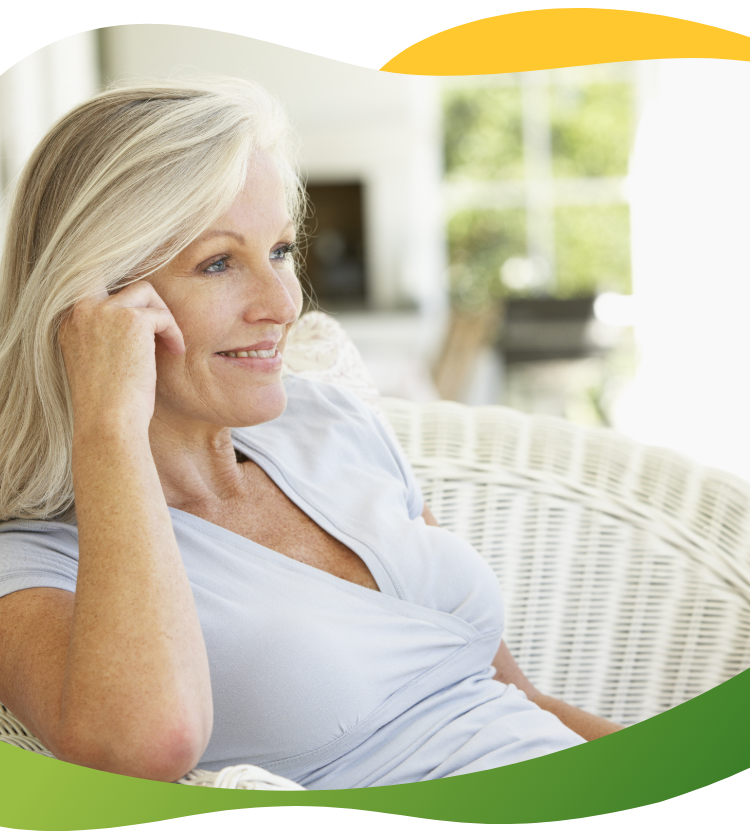 A relaxed middle-aged woman sitting on an armchair in her neat living room and talking on the phone