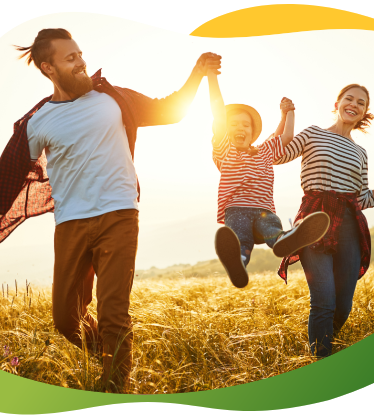 Parents running through a field with their two children and swinging one child upwards